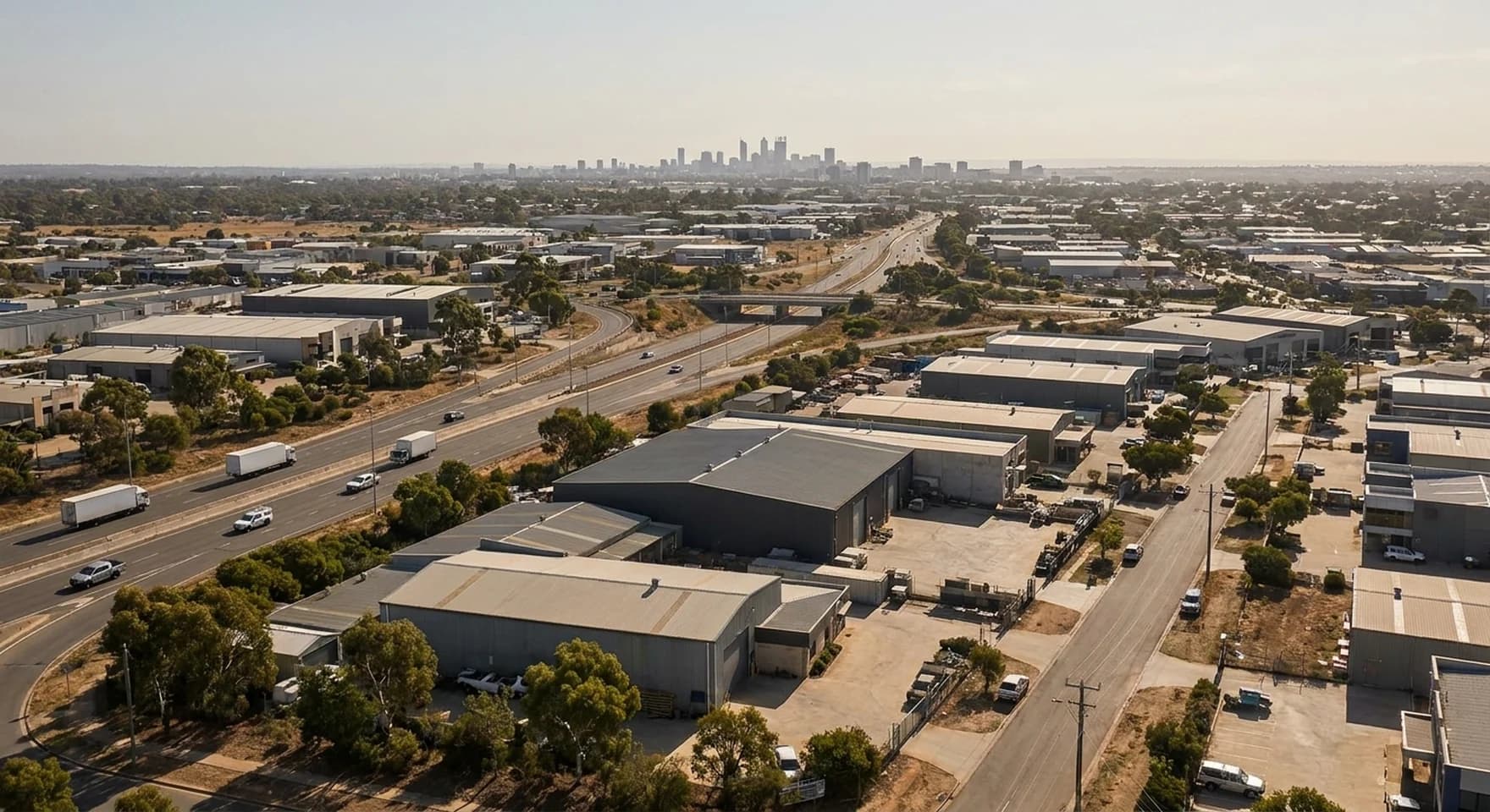 An elevated view across Perth's industrial estates and arterial roads with the city skyline on the horizon