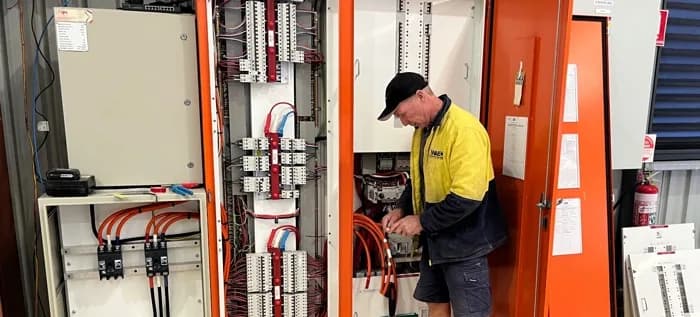Steve Randall working inside a commercial switchboard during an EV charger installation in Perth